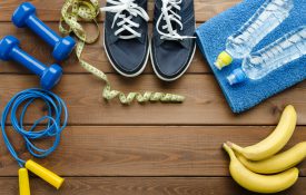 健身概念与运动鞋哑铃跳绳卷尺毛巾瓶水和香蕉在木桌背景