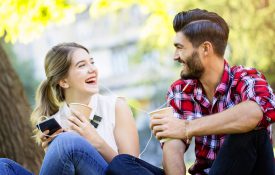 年轻的女人和年轻的男人，分享耳机和微笑