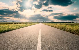 Driving on a long road towards the setting sun