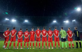 后视图的橄榄球队站在一排在比赛前国歌。