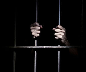 这是一张在监狱里双手握着牢房栏杆的照片。