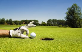 高尔夫球手把高尔夫球倒进洞里