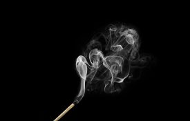 燃烧的火柴与烟卷隔离在黑色