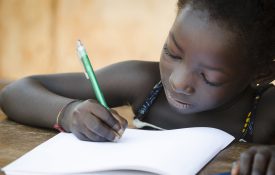 一个年轻的非洲女孩在纸上写功课。