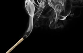 烧匹配烟孤立在黑色的卷发