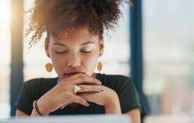 一个年轻的女商人坐在她的办公桌上，闭着眼睛思考