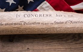 《美国独立宣言》卷在一面老式的美国国旗和乡村木板上